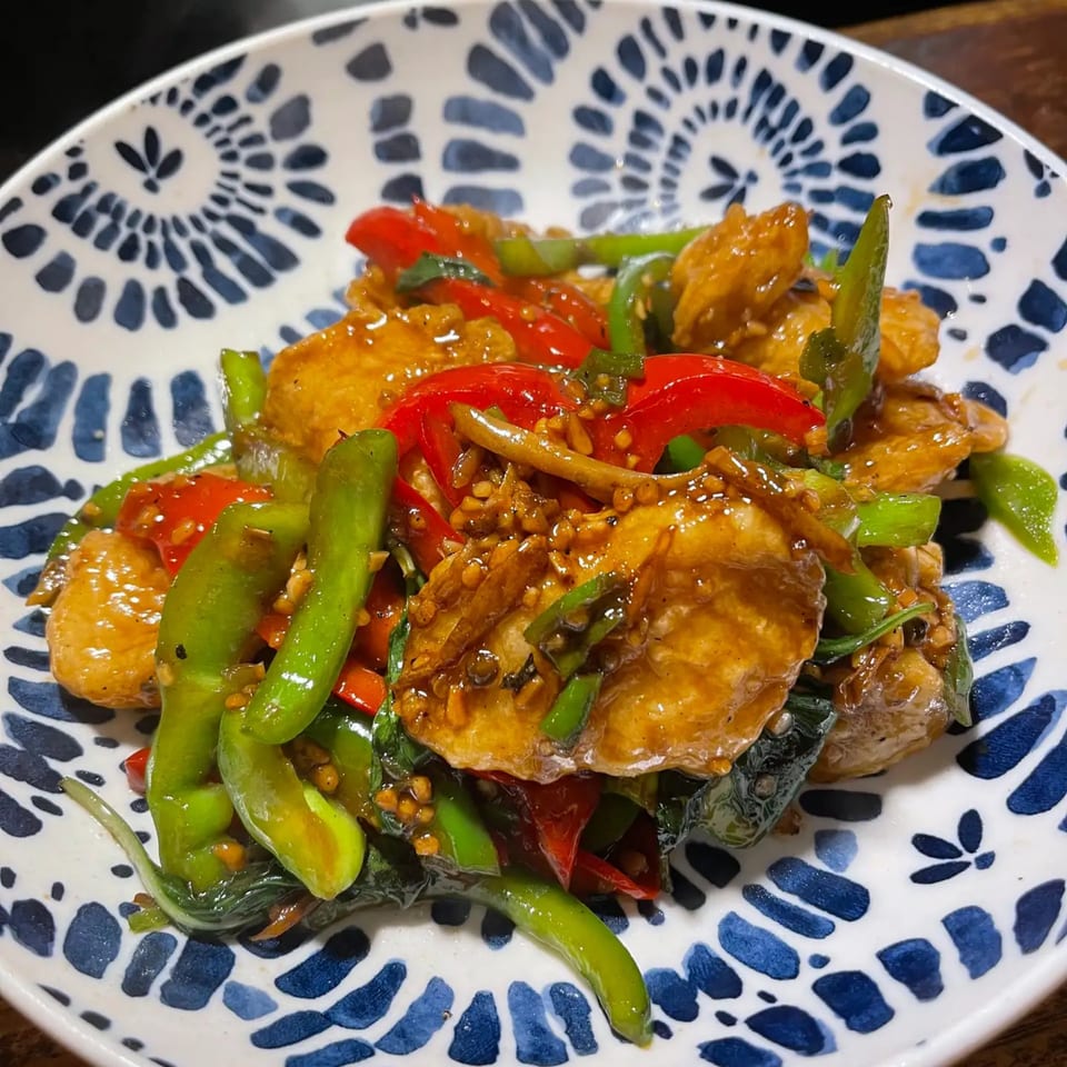 Jintana Thai Farmhouse's stir-fried chicken with red and green peppers, basil, and a glossy sauce.